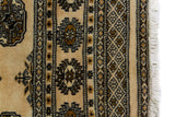 Alfombra Persa Bukara Yamouth beige de 1.24 x 1.93 mts, vista en perspectiva del campo y las guardas; el diseño muestra medallones ovalados oscuros sobre un campo beige y un marco de guardas geométricas