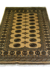 Alfombra Persa Bukara Yamouth beige de 1.24 x 1.93 mts, detalle de guarda, borde y textura; el diseño muestra medallones ovalados oscuros sobre un campo beige y un marco de guardas geométricas
