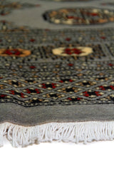 Alfombra Persa Bukara Yamouth celeste de 1.25 x 1.90 mts, detalle cercano de motivos y terminación; el diseño muestra medallones ovalados y pequeños acentos geométricos sobre un campo celeste grisáceo