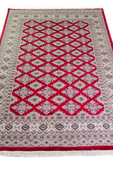 Alfombra Persa Yamouth rojo de 1.27 x 1.88 mts, vista en perspectiva del campo y las guardas; el diseño muestra una trama romboidal roja continua sobre un campo claro y un borde rojo definido