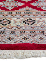 Alfombra Persa Yamouth rojo de 1.27 x 1.88 mts, detalle de guarda, borde y textura; el diseño muestra una trama romboidal roja continua sobre un campo claro y un borde rojo definido