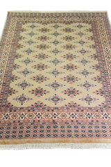 Alfombra Persa Yamouth beige de 1.27 x 1.78 mts, vista en perspectiva del campo y las guardas; el diseño muestra pequeños motivos romboidales repetidos sobre un campo beige y guardas cálidas