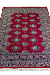 Alfombra Persa Yamouth rojo de 1.24 x 1.68 mts, vista en perspectiva del campo y las guardas; el diseño muestra medallones enlazados rojos sobre un campo claro con guardas geométricas azuladas