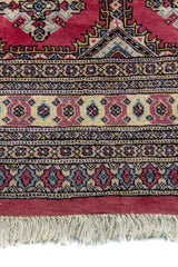 Alfombra Persa Yamouth rosa de 1.28 x 1.88 mts, detalle de guarda, borde y textura; el diseño muestra medallones rosados repetidos sobre un campo oscuro y un borde ornamental detallado