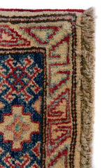Alfombra Caucasica Kazak rojo y beige de 1.17 x 1.47 mts, detalle de guarda, borde y textura; el diseño muestra medallones romboidales apilados sobre un campo rojo con amplias guardas beige