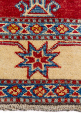 Alfombra Caucasica Kazak bordó y beige de 1.14 x 1.65 mts, detalle de guarda, borde y textura; el diseño muestra un gran motivo central de lectura geométrica sobre un campo bordó y guardas beige