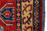 Alfombra Caucasica Kazak ladrillo y beige de 1.07 x 1.45 mts, detalle de guarda, borde y textura; el diseño muestra un medallón central azul rodeado por motivos geométricos sobre un campo ladrillo