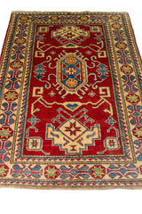 Alfombra Caucasica Kazak ladrillo y beige de 1.09 x 1.58 mts, vista en perspectiva del campo y las guardas; el diseño muestra medallones geométricos escalonados sobre un campo ladrillo con guardas claras y pequeños acentos