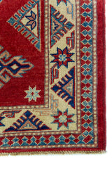 Alfombra Caucasica Kazak ladrillo y beige de 1.04 x 1.47 mts, detalle de guarda, borde y textura; el diseño muestra tres medallones geométricos principales sobre un campo ladrillo con borde beige