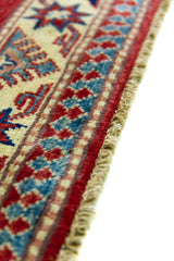 Alfombra Caucasica Kazak ladrillo y beige de 1.04 x 1.47 mts, detalle cercano de motivos y terminación; el diseño muestra tres medallones geométricos principales sobre un campo ladrillo con borde beige