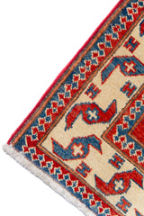 Alfombra Caucasica Kazak rojo y beige de 0.91 x 1.60 mts, detalle de guarda, borde y textura; el diseño muestra tres medallones geométricos destacados sobre un campo rojo con amplias guardas beige