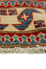 Alfombra Caucasica Kazak rojo y beige de 0.91 x 1.60 mts, detalle cercano de motivos y terminación; el diseño muestra tres medallones geométricos destacados sobre un campo rojo con amplias guardas beige