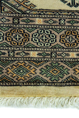 Alfombra Persa Yamouth verde y beige de 0.76 x 1.14 mts, detalle de guarda, borde y textura; el diseño muestra una cadena central de grandes rombos beige sobre un campo verde oscuro con guardas geométricas