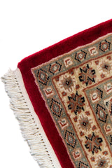Alfombra Persa Yamouth beige y rojo de 0.61 x 1.09 mts, detalle de guarda, borde y textura; el diseño muestra un motivo enlazado rojo de gran escala sobre un campo beige y un borde rojo intenso