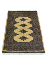 Alfombra Persa Yamouth gris y beige de 0.80 x 1.22 mts, vista en perspectiva del campo y las guardas; el diseño muestra grandes rombos beige enlazados sobre un campo gris oscuro con un marco geométrico estrecho