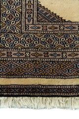 Alfombra Persa Yamouth gris y beige de 0.80 x 1.22 mts, detalle de guarda, borde y textura; el diseño muestra grandes rombos beige enlazados sobre un campo gris oscuro con un marco geométrico estrecho
