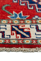 Alfombra Caucasica Kazak ladrillo y azul de 0.61 x 1.30 mts, detalle de guarda, borde y textura; el diseño muestra tres medallones geométricos de gran escala sobre un campo ladrillo con acentos azules