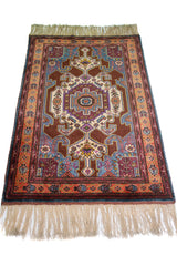 Alfombra Caucasica Kazak marrón y naranja de 0.97 x 1.63 mts, vista en perspectiva del campo y las guardas; el diseño muestra un medallón central y motivos angulares sobre un campo marrón con guardas naranjas
