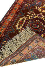 Alfombra Caucasica Kazak marrón y naranja de 0.97 x 1.63 mts, detalle cercano de motivos y terminación; el diseño muestra un medallón central y motivos angulares sobre un campo marrón con guardas naranjas