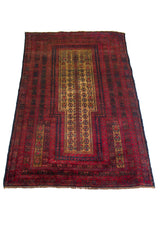 Alfombra Persa Baluchistán Oración rojo y marrón de 0.85 x 1.45 mts, vista en perspectiva del campo y las guardas; el diseño muestra un campo rojo profundo con panel central estrecho y bandas geométricas repetidas de inspiración de oración