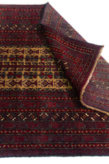Alfombra Persa Baluchistán Oración bordó y marrón de 0.95 x 1.47 mts, detalle cercano de motivos y terminación; el diseño muestra un panel central estrecho sobre un campo bordó con bandas geométricas repetidas de inspiración de oración