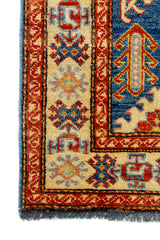 Alfombra Caucasica Kazak beige y azul de 0.83 x 1.30 mts, detalle de guarda, borde y textura; el diseño muestra medallones geométricos azules sobre un campo beige con guardas de acento ladrillo
