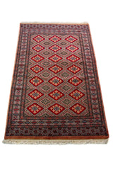 Alfombra Persa Bukara rojo de 0.92 x 1.55 mts, detalle cercano de los motivos del campo y la combinación de tonos