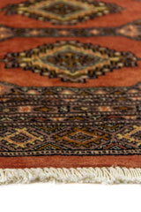 Alfombra Persa Bukara rosa viejo y gris de 0.63 x 0.90 mts, detalle cercano de los motivos del campo y la combinación de tonos