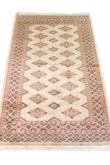 Alfombra Persa Bukara blanco y beige de 0.92 x 1.55 mts, vista en perspectiva que permite apreciar el campo central y las guardas