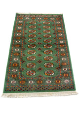 Alfombra Persa Bukara verde oscuro de 0.97 x 1.55 mts, detalle cercano de los motivos del campo y la combinación de tonos