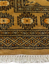 Alfombra Persa Bukara mostaza y beige de 0.76 x 1.27 mts, detalle cercano de los motivos del campo y la combinación de tonos