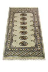 Alfombra Persa Bukara verde y negro de 0.59 x 1.24 mts, vista en perspectiva que permite apreciar el campo central y las guardas