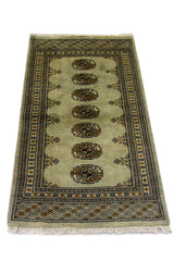 Alfombra Persa Bukara verde y negro de 0.59 x 1.24 mts, detalle cercano de los motivos del campo y la combinación de tonos
