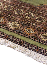 Alfombra Persa Bukara verde y rosa de 0.76 x 1.30 mts, detalle de guarda, trama visual y terminación de borde