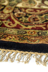 Primer plano de flecos y terminación de alfombra redonda con textura aterciopelada en color negro.