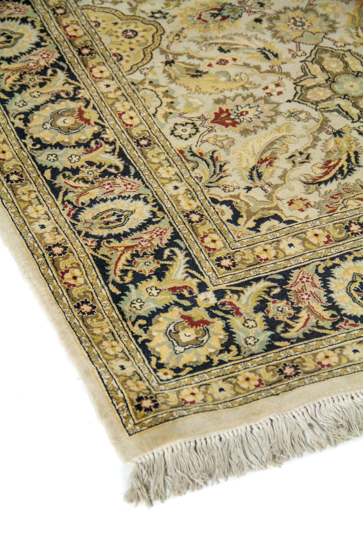 Vista en ángulo de alfombra clásica con fondo beige, dibujo floral elegante y guarda oscura con detalles tradicionales.