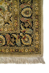 Primer plano de esquina de alfombra oriental con marco oscuro, ornamentos florales y terminación con flecos beige.
