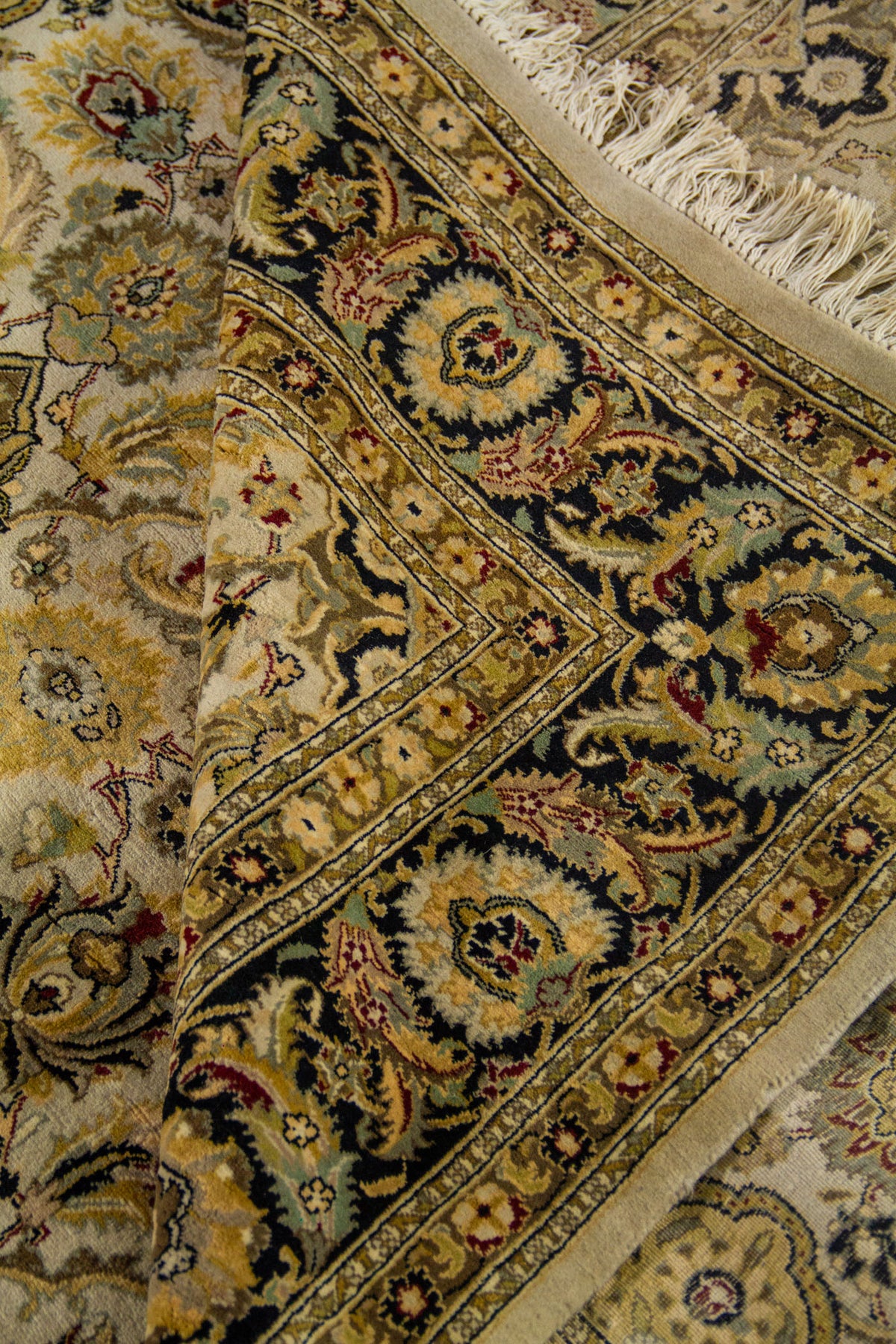 Alfombra doblada mostrando la flexibilidad del tejido, los detalles del borde decorativo y el acabado artesanal con flecos.