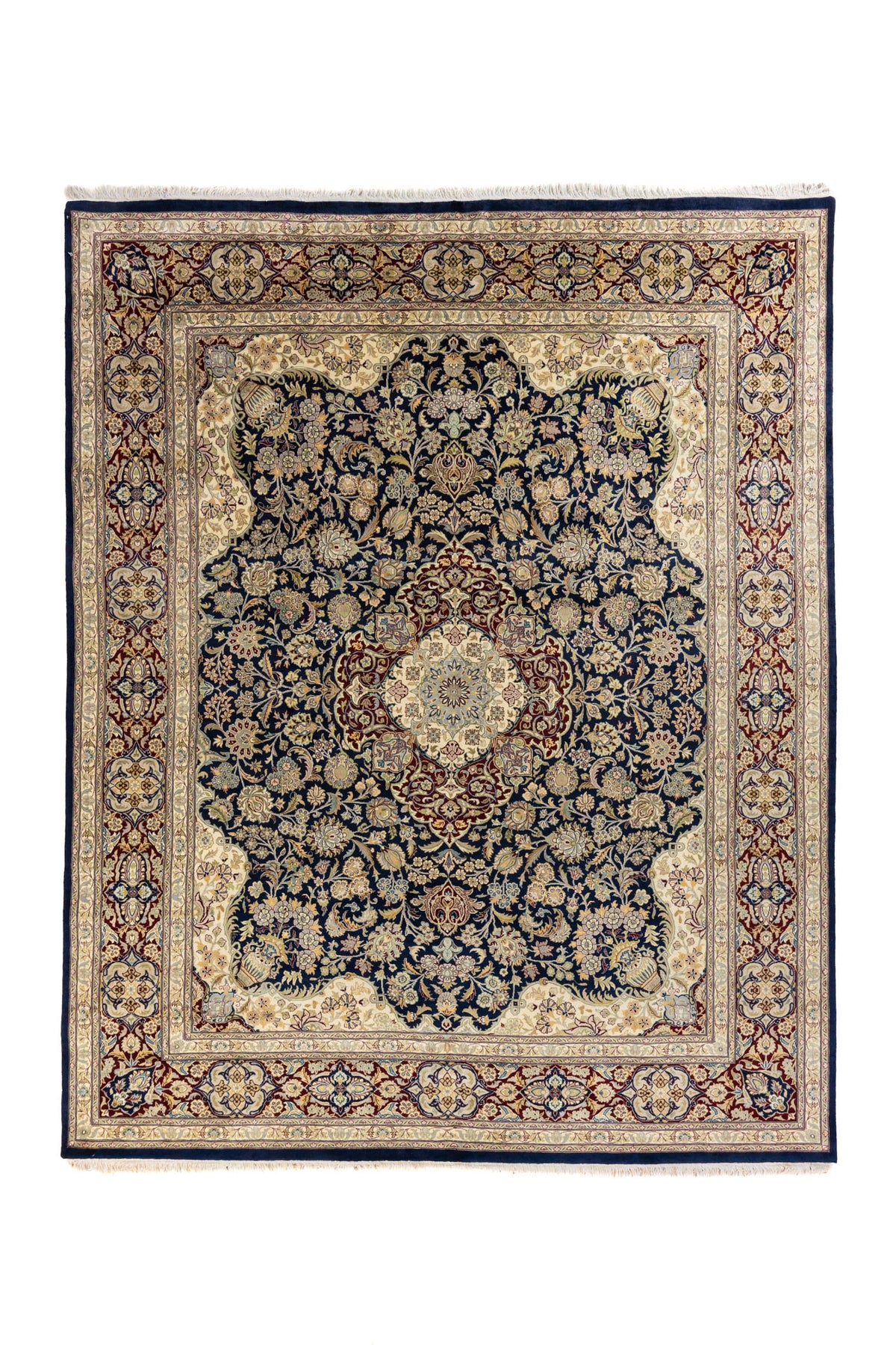 Alfombra clásica oriental con medallón central, fondo azul marino y guarda beige con detalles en rojo