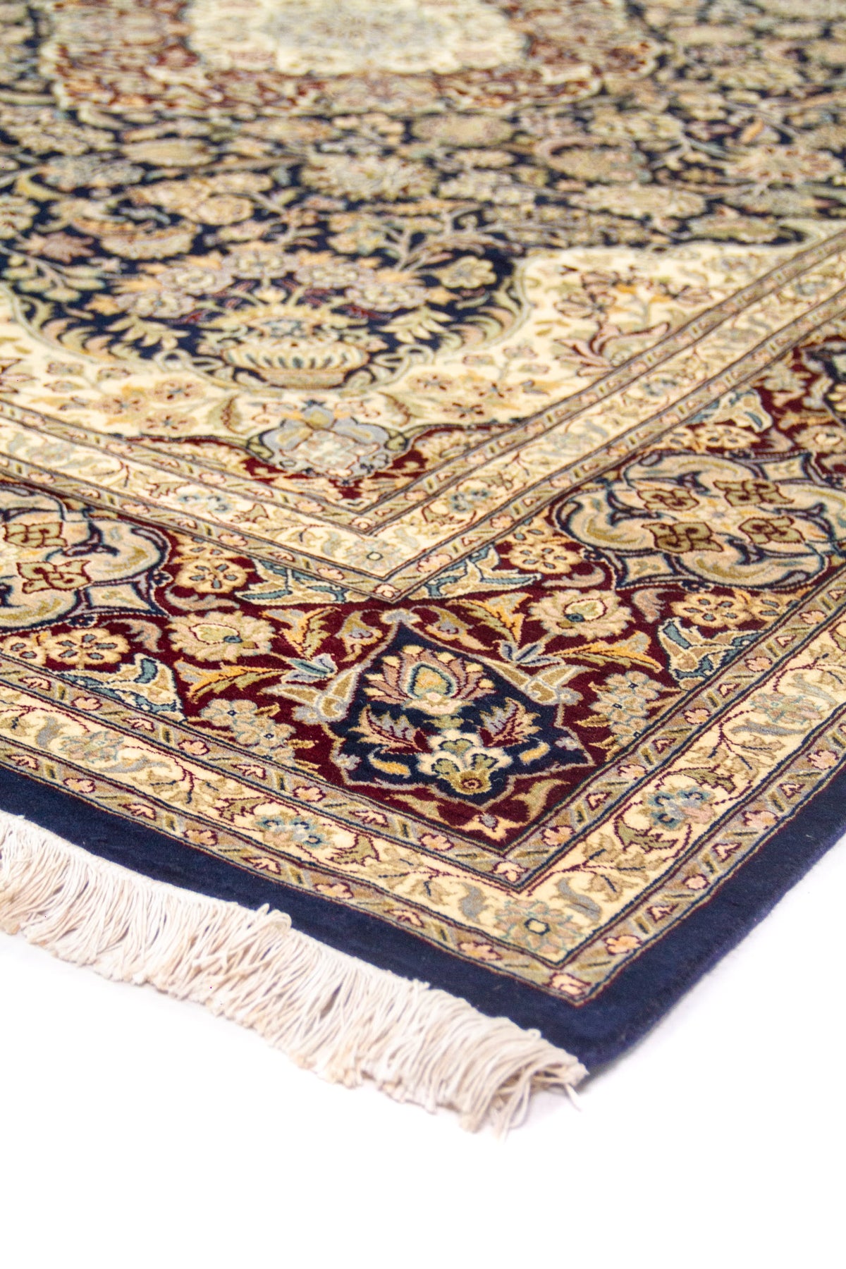 Detalle de esquina con flecos beige, borde azul oscuro y franjas beige con motivos florales