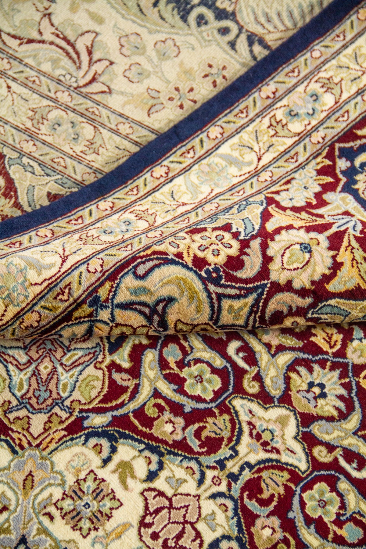 Esquina doblada mostrando grosor y textura, fondo azul marino con motivos florales clásicos