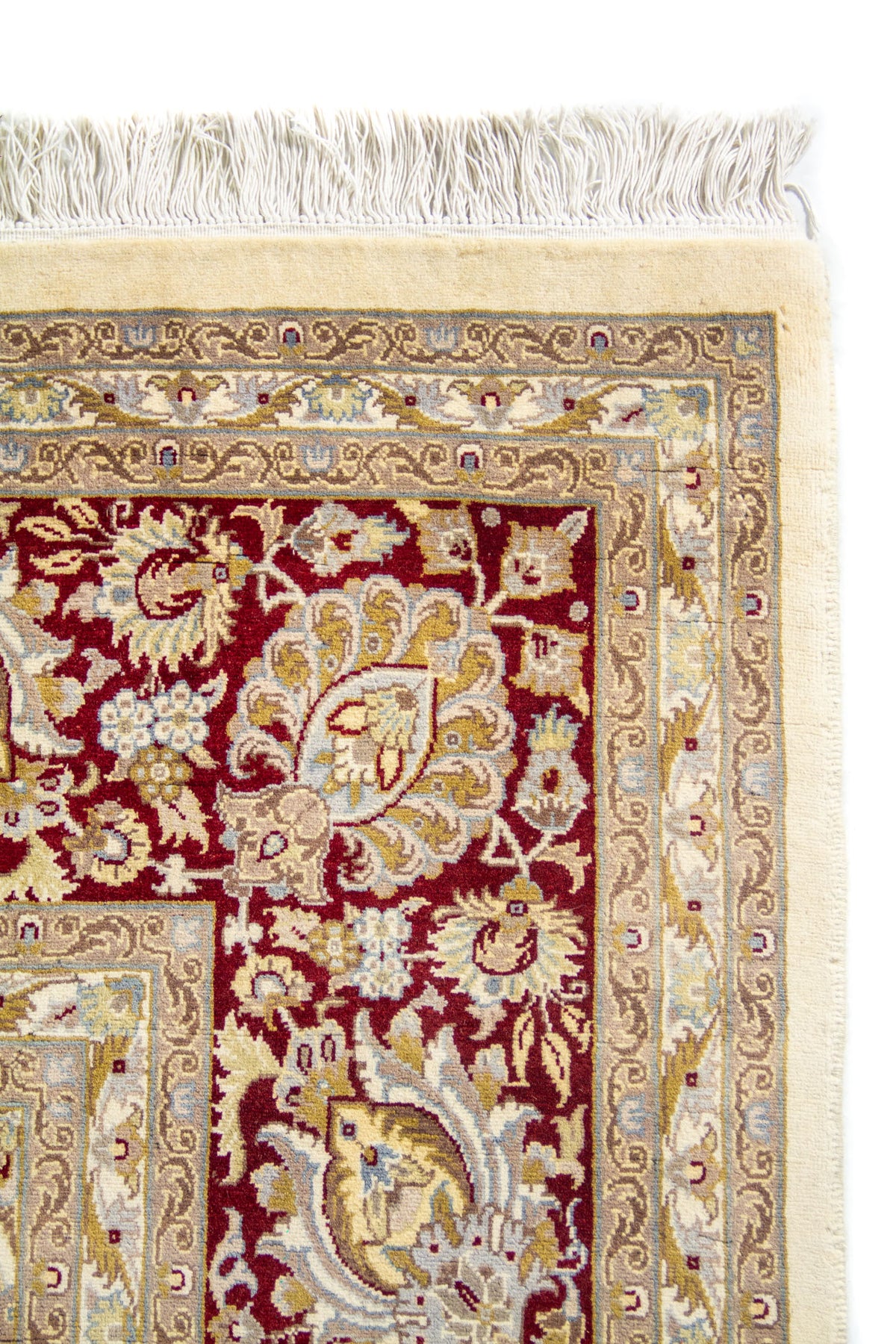 Detalle de esquina con flecos blanco y franjas en beige y celeste sobre marco rojo oscuro.