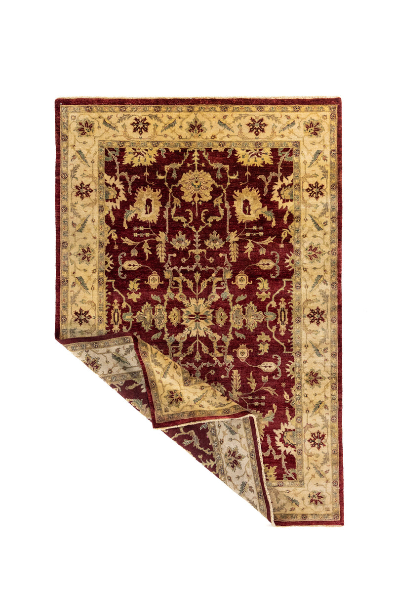 Alfombra roja con una esquina levantada, mostrando el reverso, la flexibilidad del tejido y el acabado con flecos.