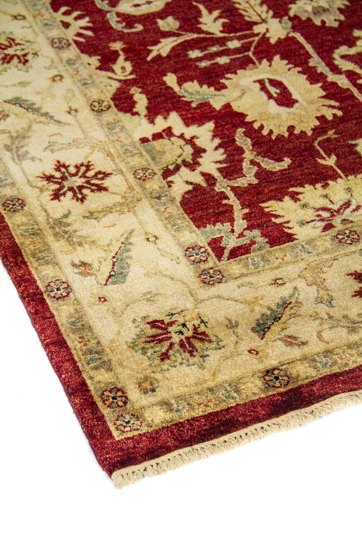 Vista en ángulo de alfombra oriental con campo rojo oscuro, guarda beige ornamental y delicados motivos florales.