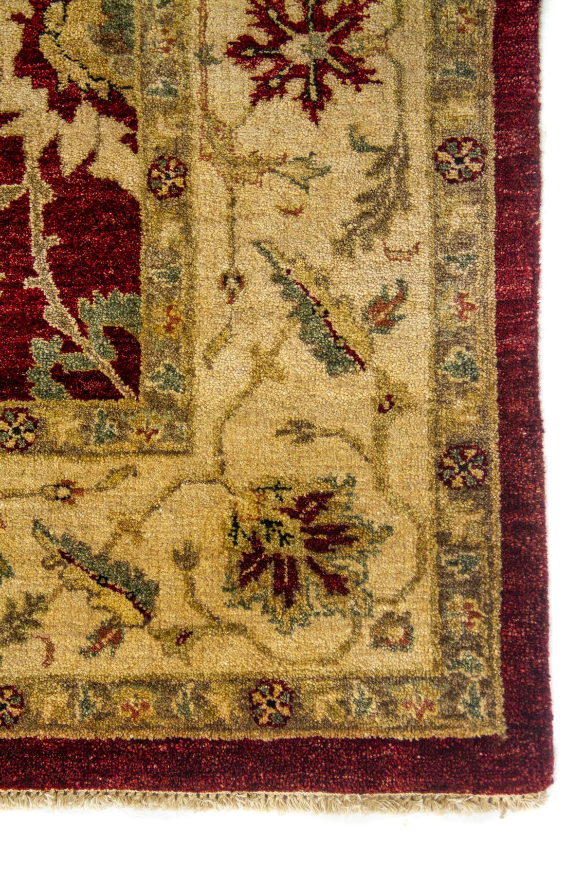 Primer plano de esquina de alfombra clásica con borde rojo, marco beige y detalles decorativos en tonos suaves.