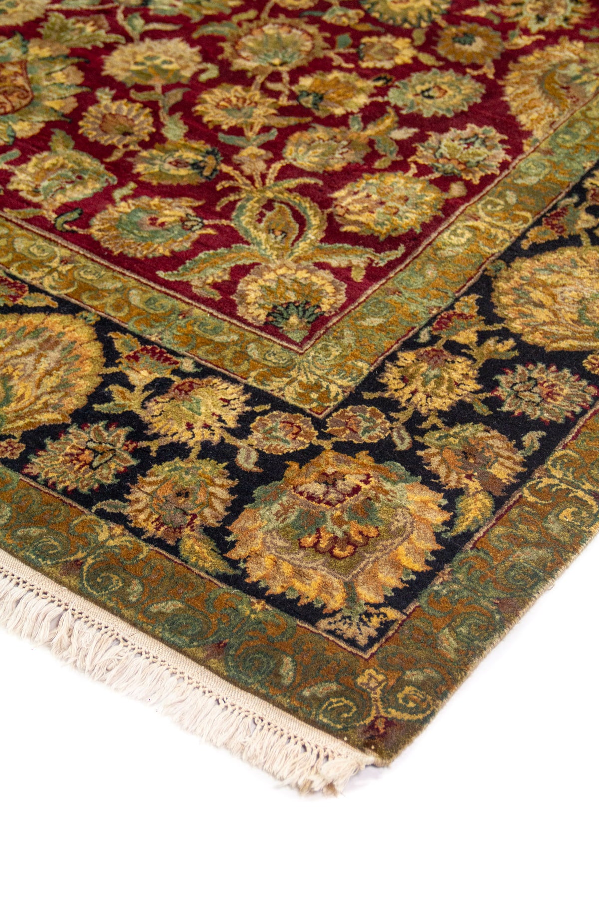 Detalle de esquina de alfombra oriental con fondo rojo intenso, motivos florales y guarda negra con flores grandes