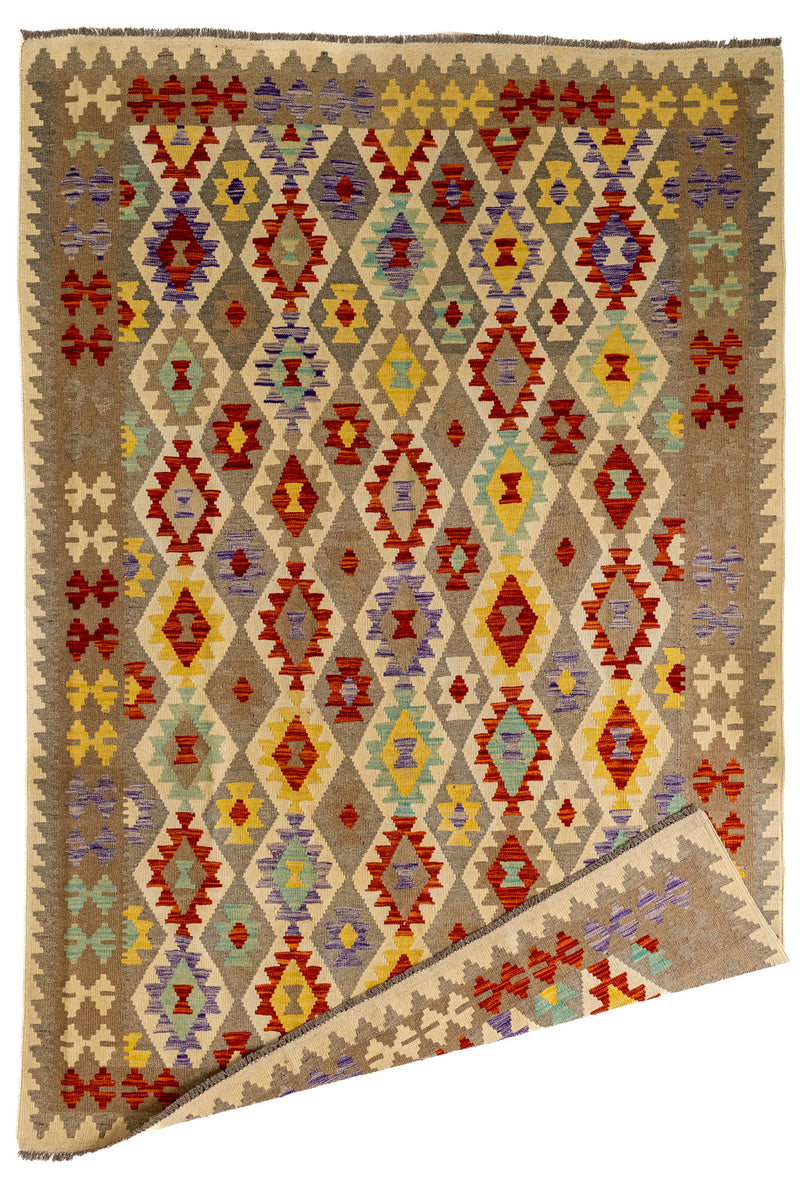 Vista general de alfombra kilim con una esquina doblada, mostrando el reverso del tejido y su carácter reversible.