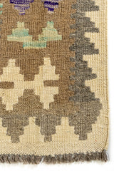 Detalle del borde inferior izquierdo de la alfombra kilim, mostrando el acabado con flecos y la transición de colores terrosos.