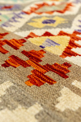 Alfombra en ángulo bajo que resalta la textura tejida a mano de la alfombra y los patrones en rojo y beige.