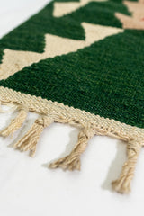 Detalle de los flecos y del borde tejido de la alfombra kilim en tonos beige y verde intenso.